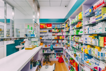A photo of a pharmacy showing shelves of medicine behind a counter